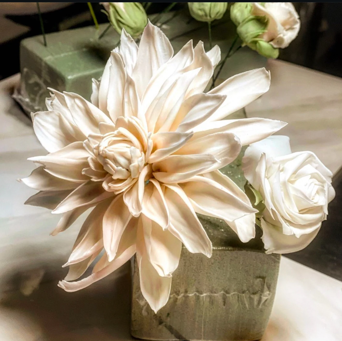 An arrangement of sculpted sugar flowers in a ceramic vase