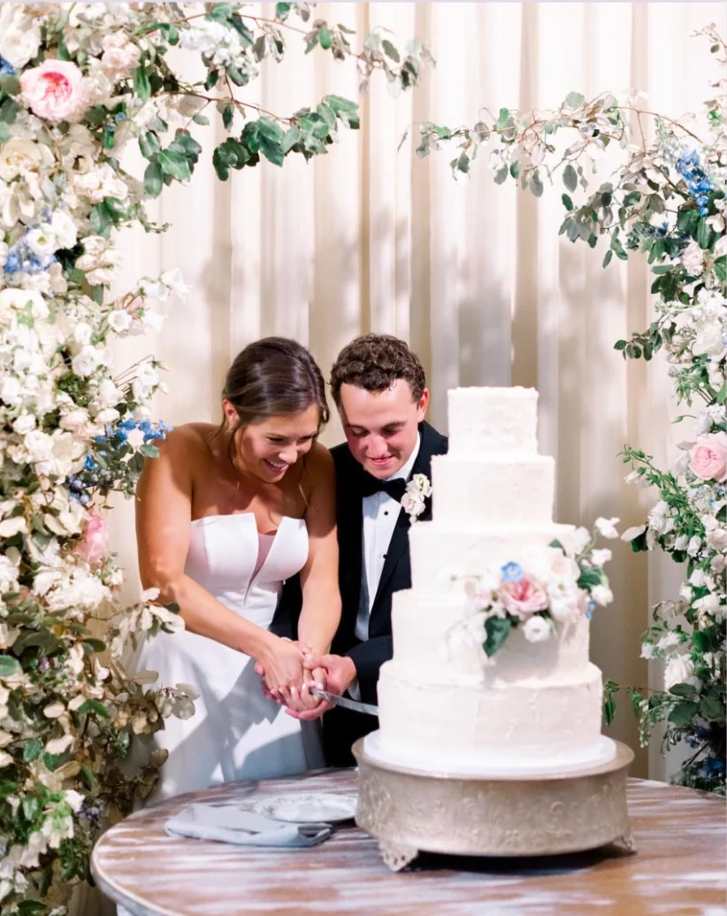 A couple shares a moment beside their wedding cake